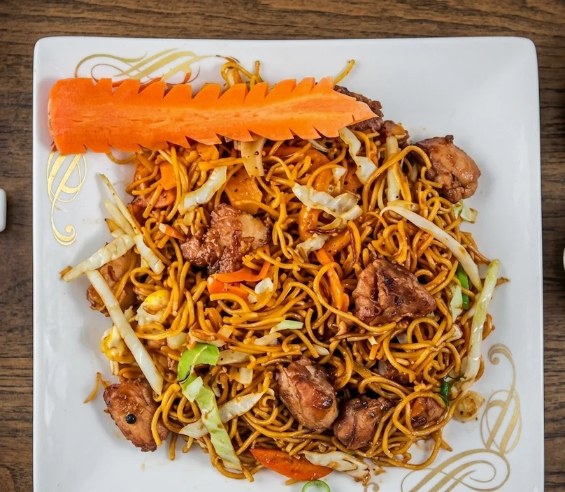 Stir-fried noodles with meat, cabbage and a carved carrot